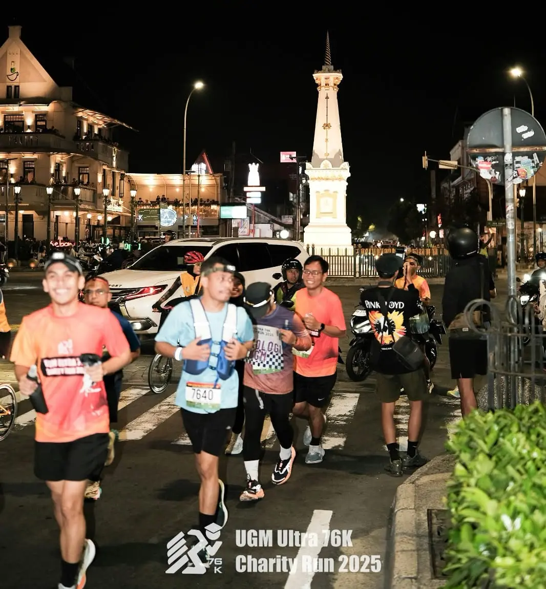 Pelari UGM Ultra 76K tersenyum melintas di depan Tugu Yogyakarta pada malam hari
